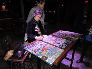 Bonnie MacLean signs copies of the poster she created to commemorate the opening of the Philadelphia Fillmore. With Bonnie is her son, David Graham. (Photo by Mike Morsch)